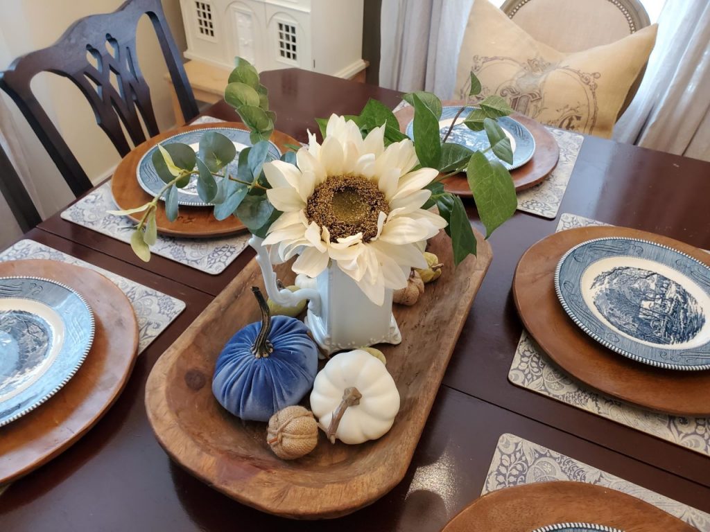 Adding a large flowy white sunflower to the centerpiece as I set the table for the fall season.