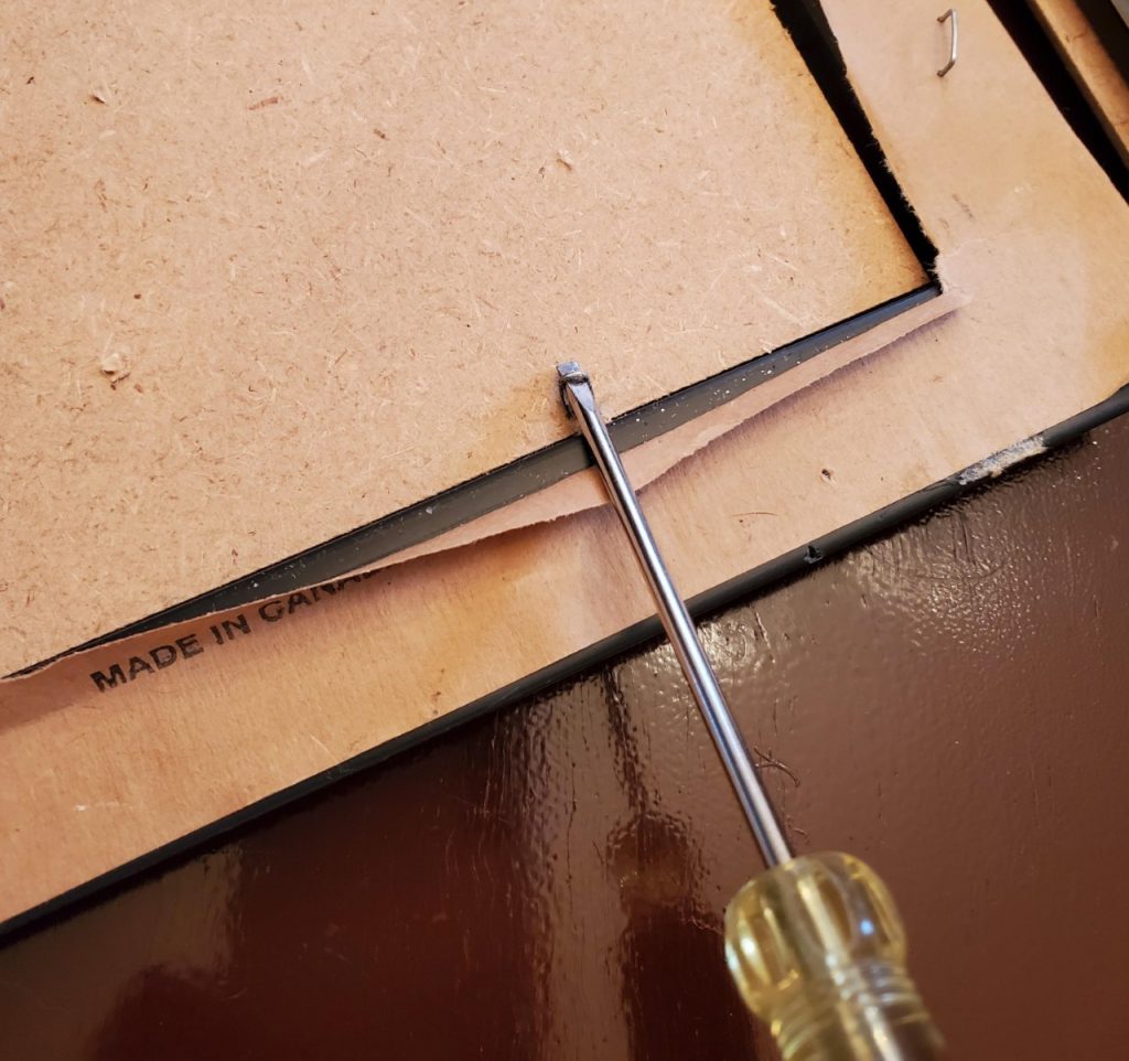 Removing the staples from a Goodwill frame to give it a makeover.