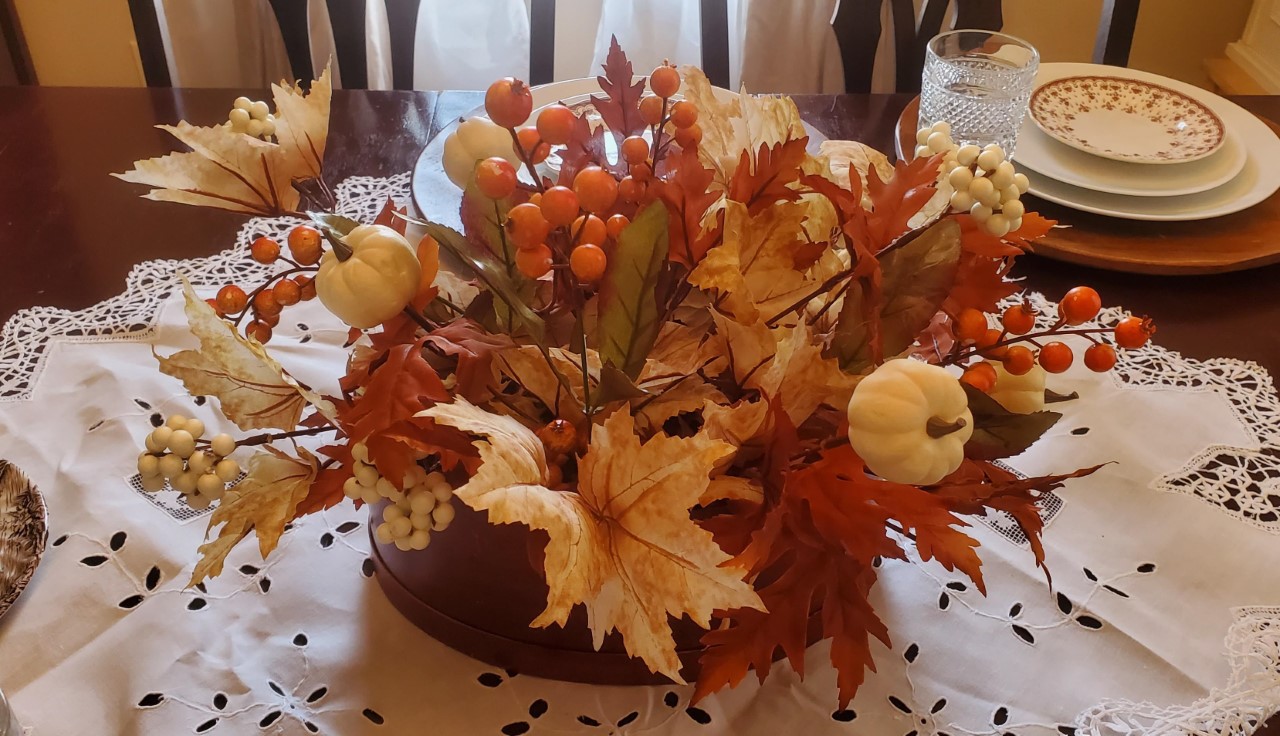 Leaves and berries added to a hat box to make a centerpiece.