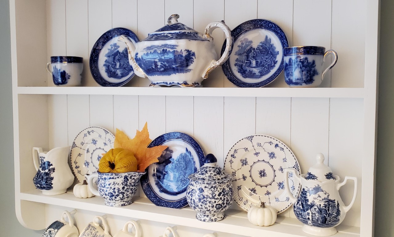 Breakfast nook shelf displaying blue dishes. Added a pumpkin to a creamer to decorate for fall.