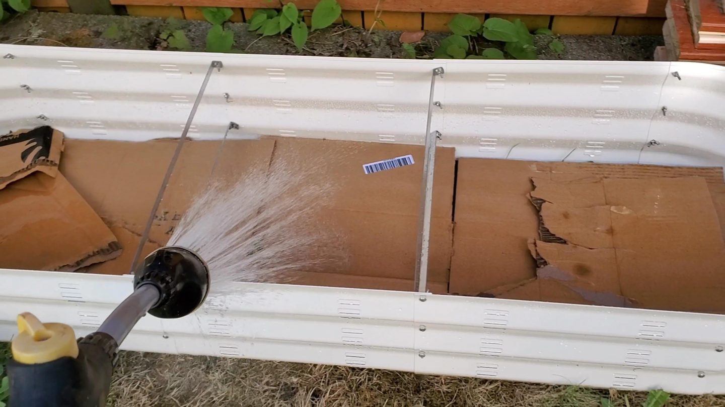 Watering the cardboard before we add the dirt to the raised beds.