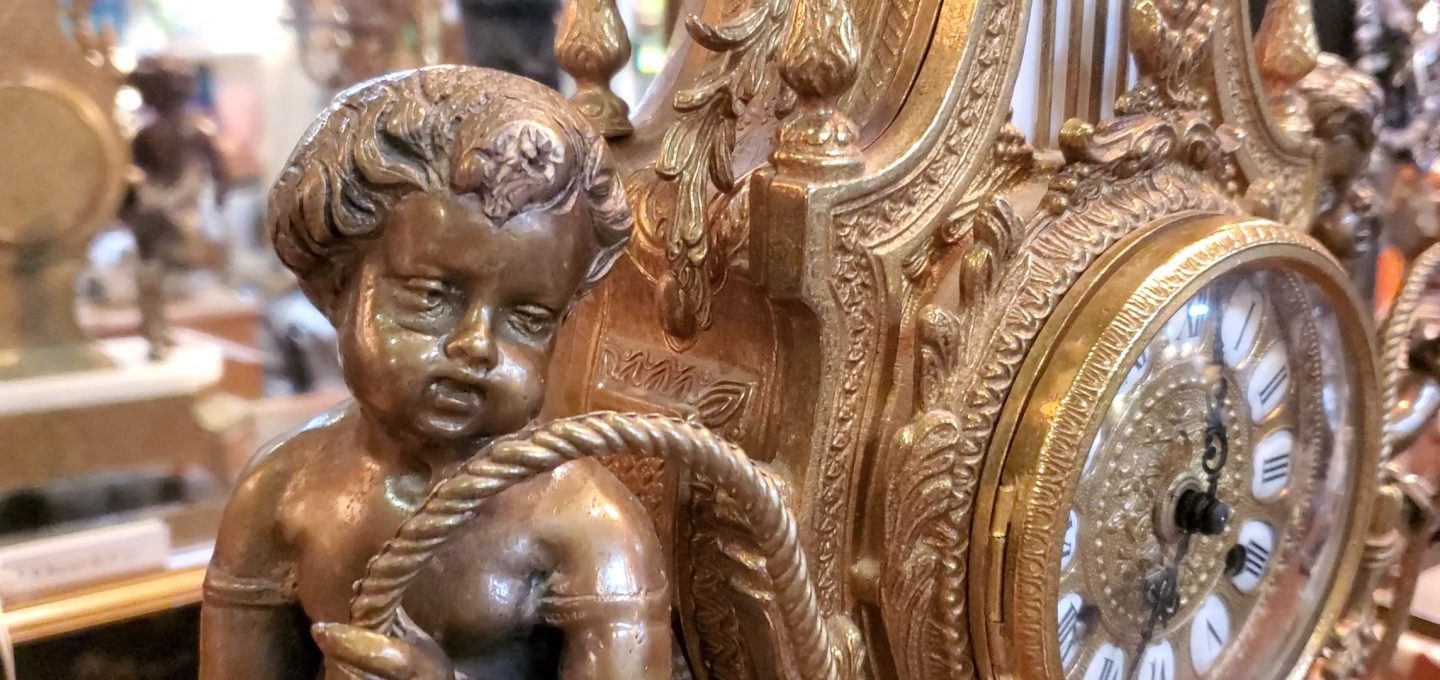 Up close photo of a cherub on the side of an antique French Imperial clock.