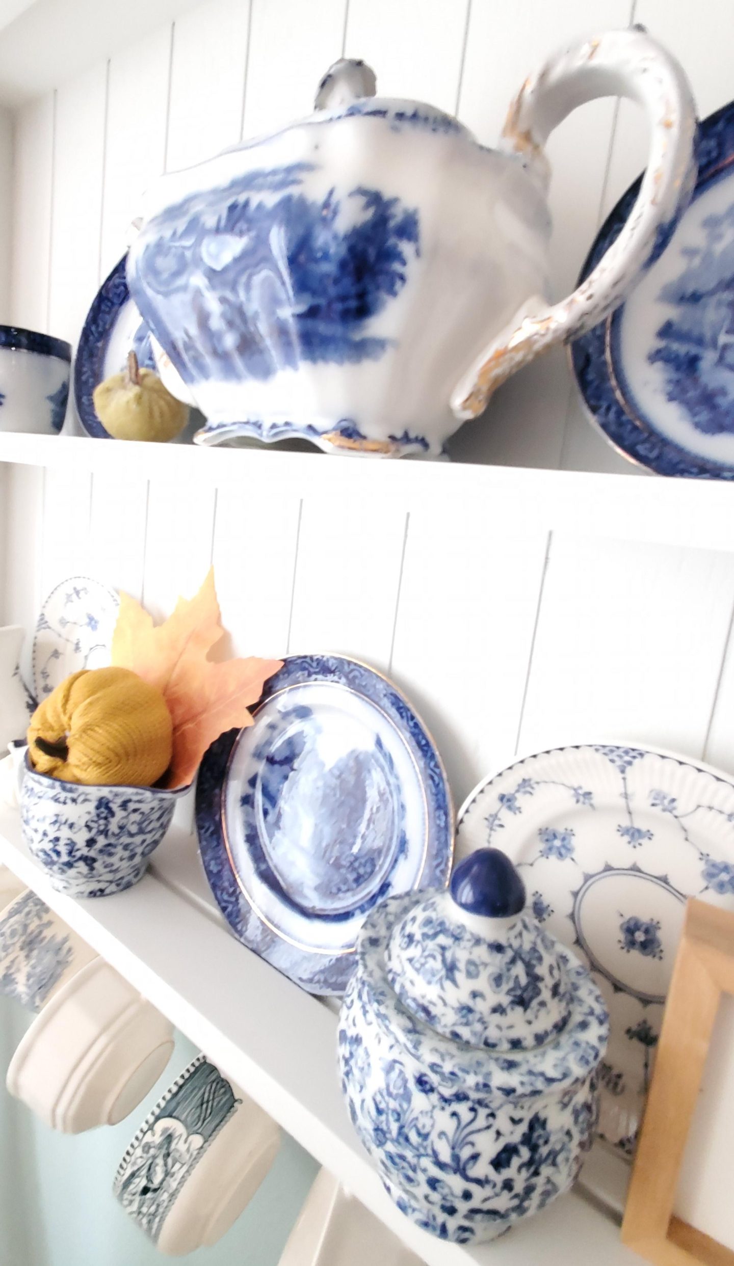 Photo of blue dishes on a shelf. Added a pumpkin to a creamer to decorate for fall.