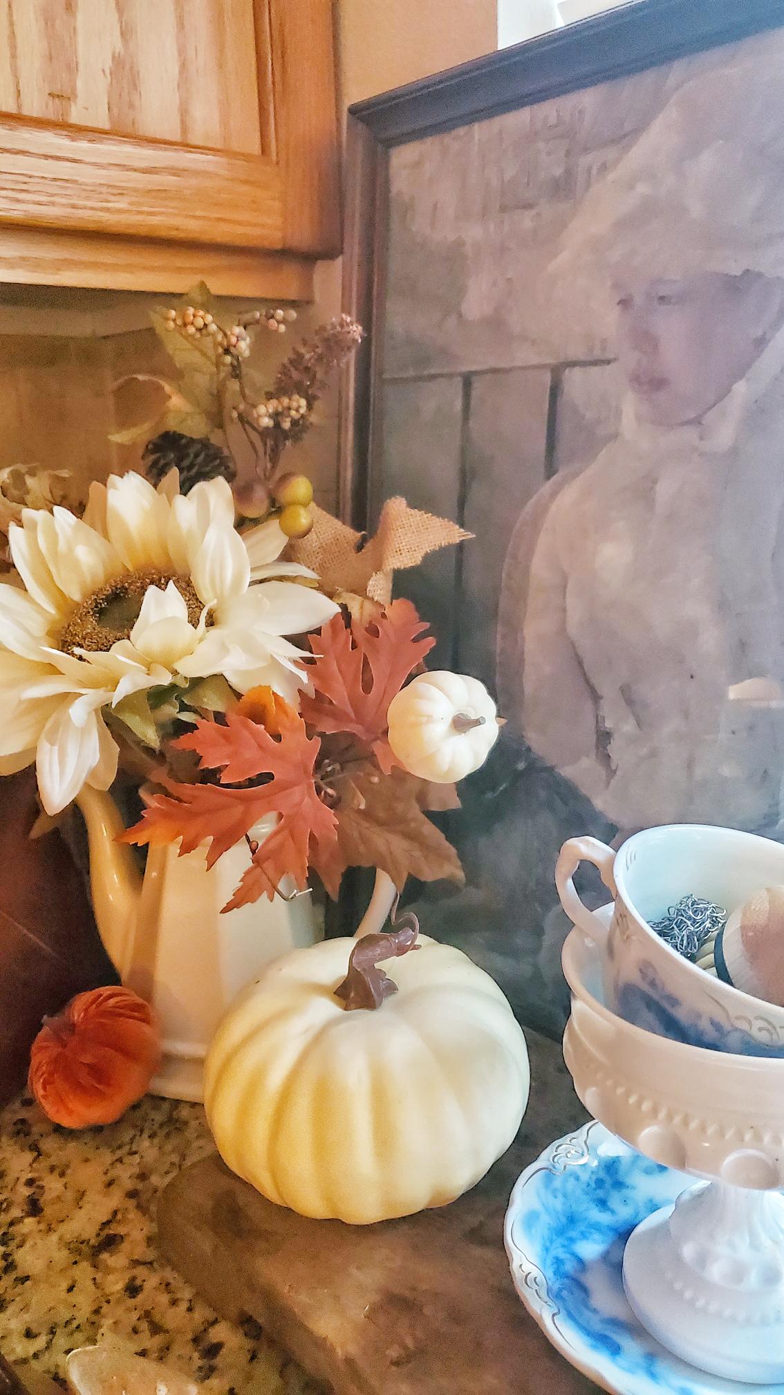Bouquet of flowers in our kitchen. With a vintage print in the background. A large white pumpkin on top of a wooden block.